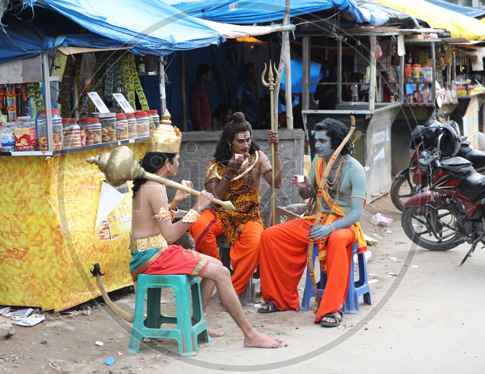 Man in Indian  Mythology  Gods  Makeup Having Tea By Sitting at a tea Stall