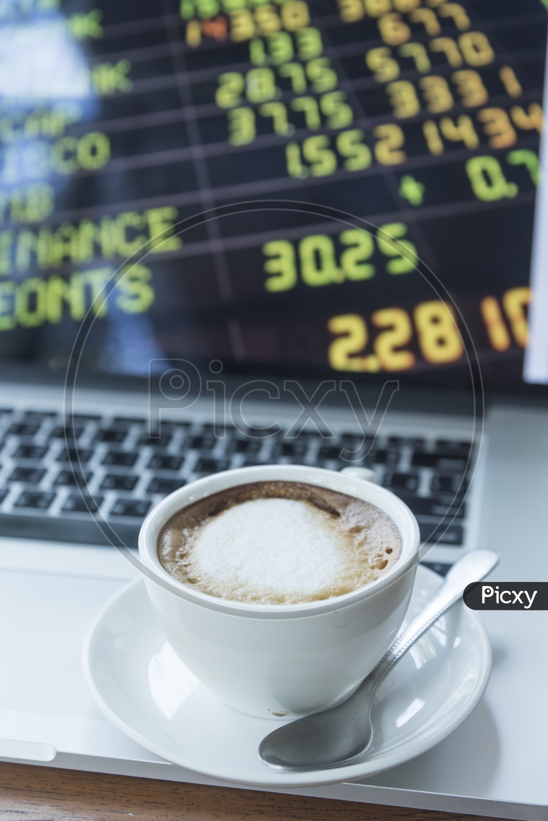 A Coffee Cup with Stock Markets Data on Laptop Screen