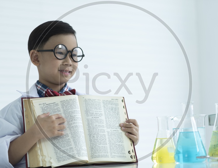 Asian nerdy boy holding a textbook in the classroom