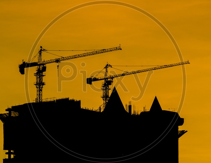 Silhouettes of Tower Cranes at construction site during sunset