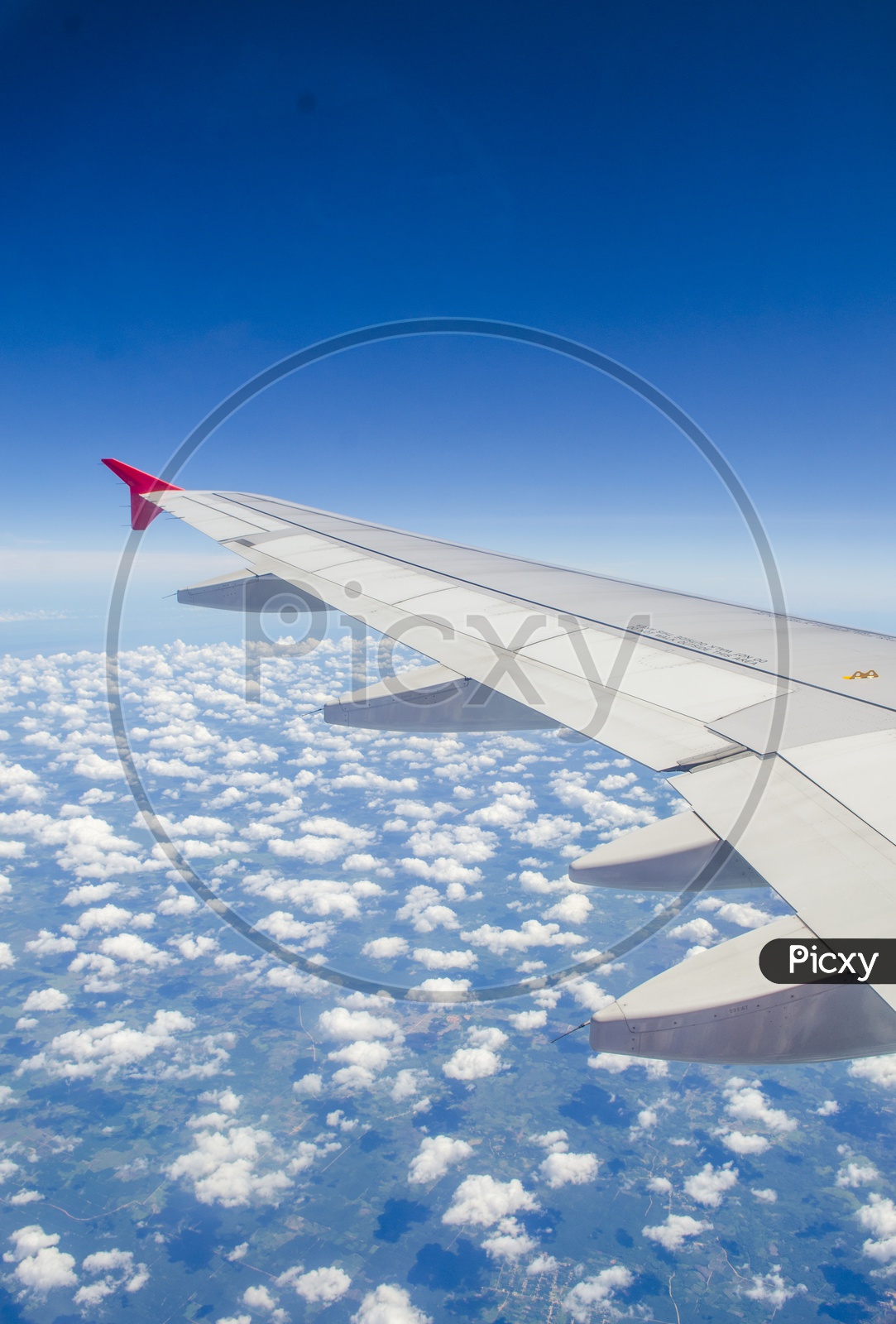 Wing of an airplane with blue sky and cotton candy clouds