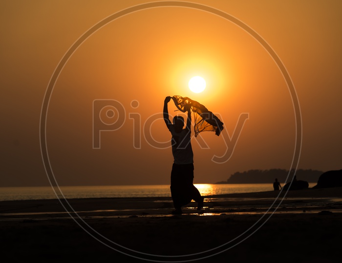 Silhouette of a man running with a scarf during sunset in Thailand