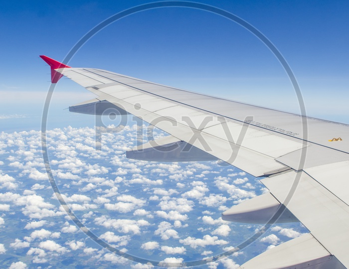 Wing of an airplane with blue sky and cotton candy clouds
