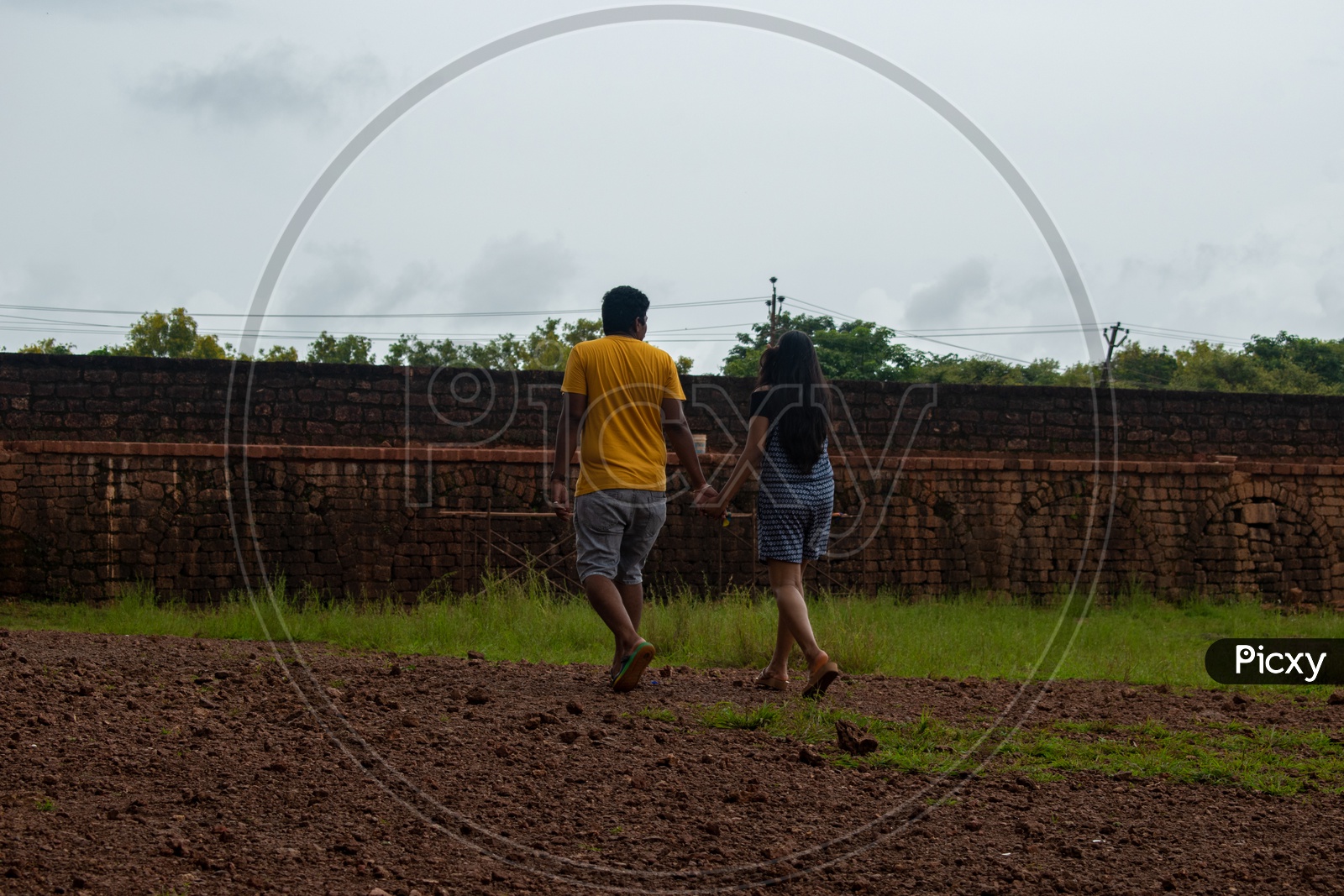 Couple holding hands and walking at Aguada Fort.
