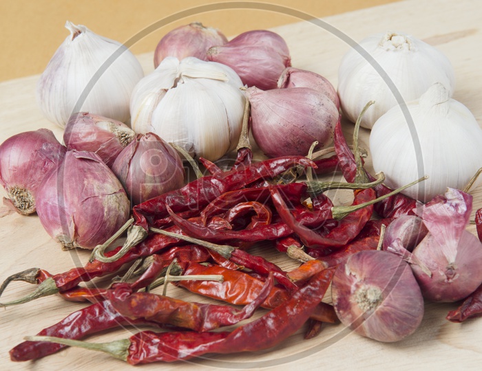 Red Chilies, Onions and Garlic on wooden background