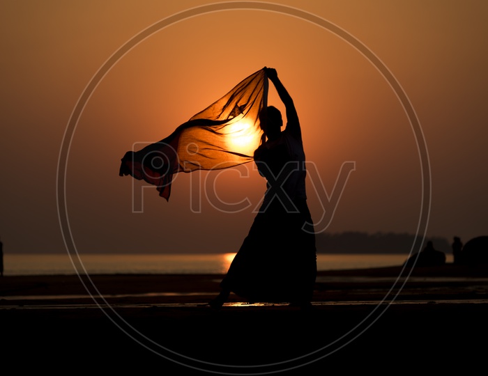 Silhouette of a man playing with scarf during sunset in Thailand