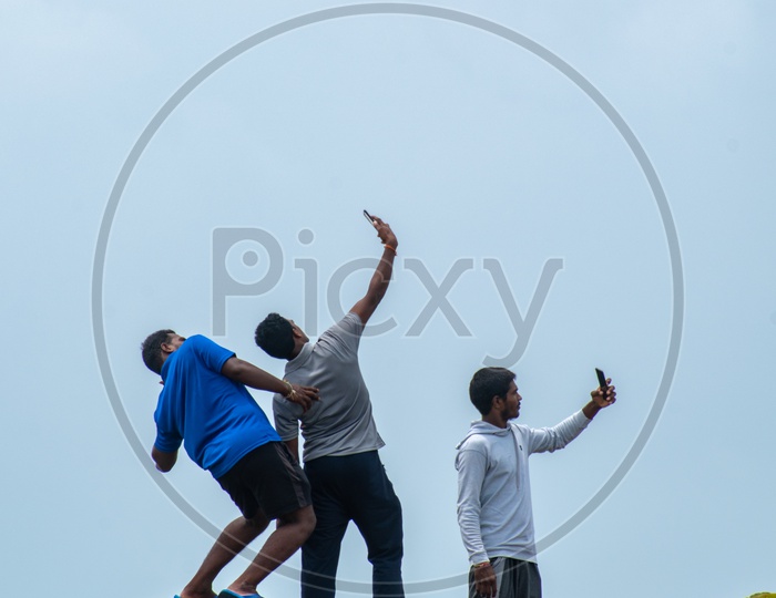 Young boys/men clicking selfies on the wall of Chapora Fort, Goa.