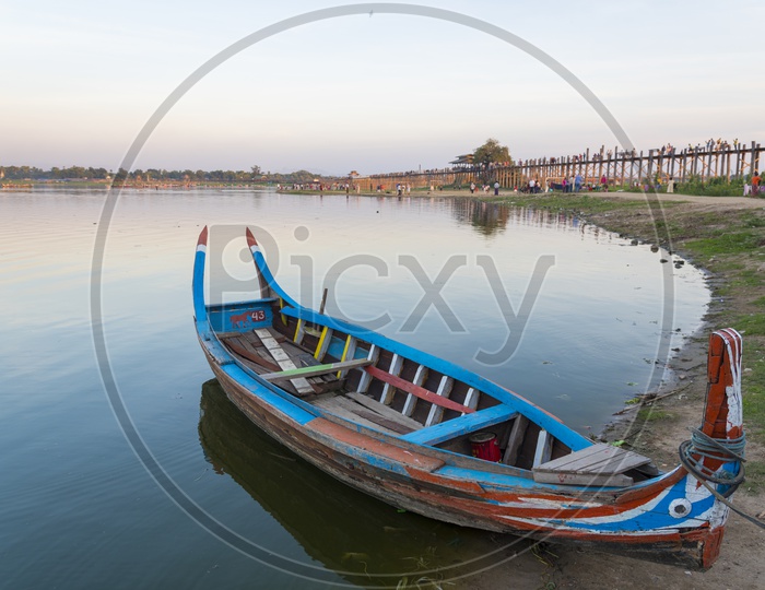 Wooden boat alongside the Ubein Bridge during sunrise in  Mandalay, Myanmar