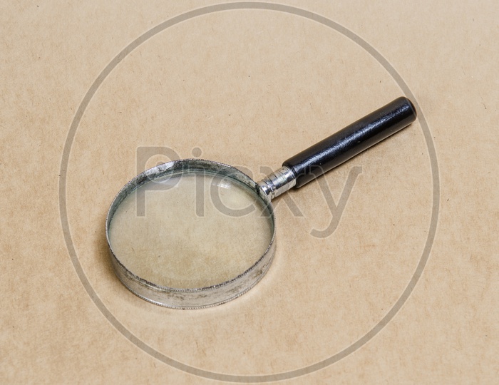 Old magnifying glass on vintage paper background