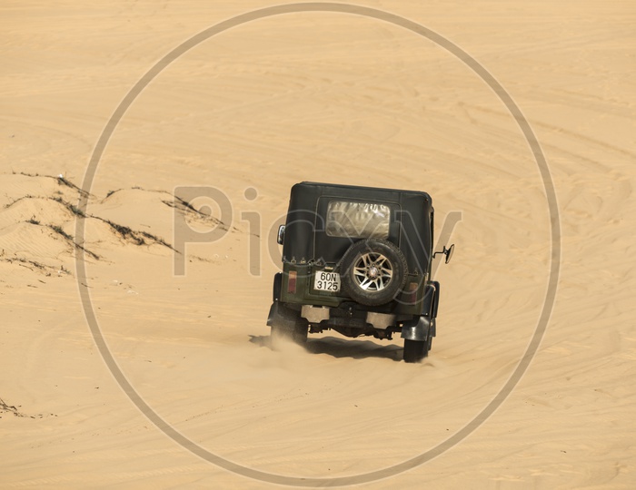 Tourists enjoy in the desert by jeep car in Mui Ne, Vietnam
