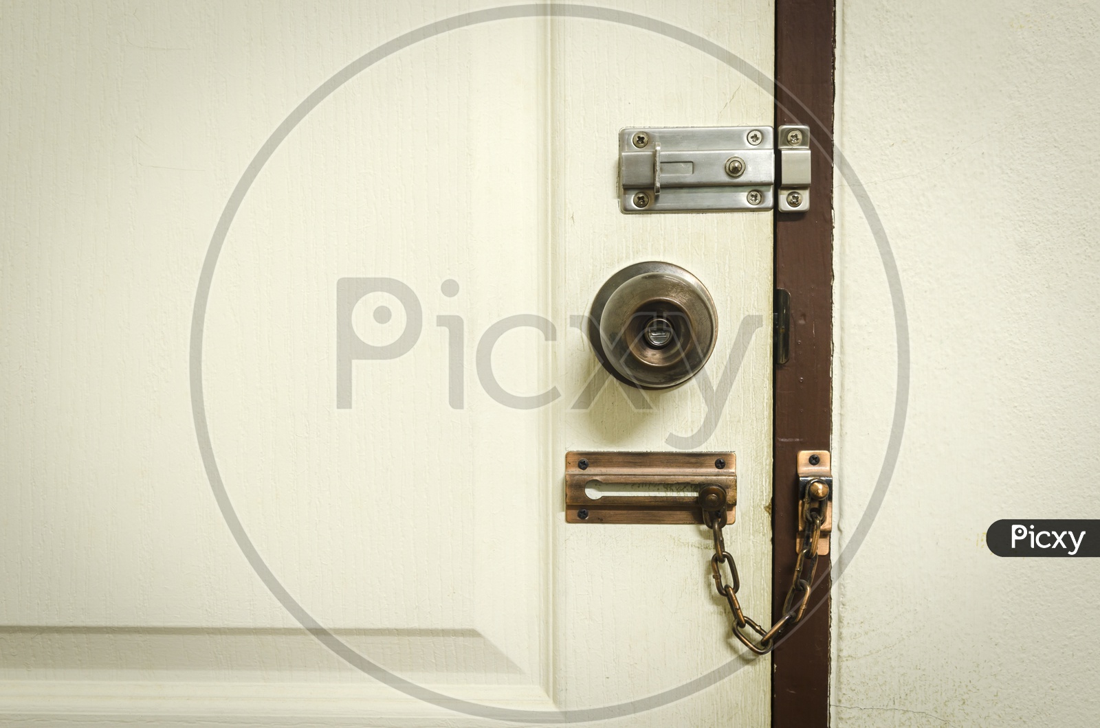 A Padlock on white door with chain
