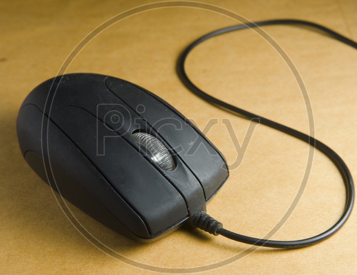 A Black computer wired mouse on brown background