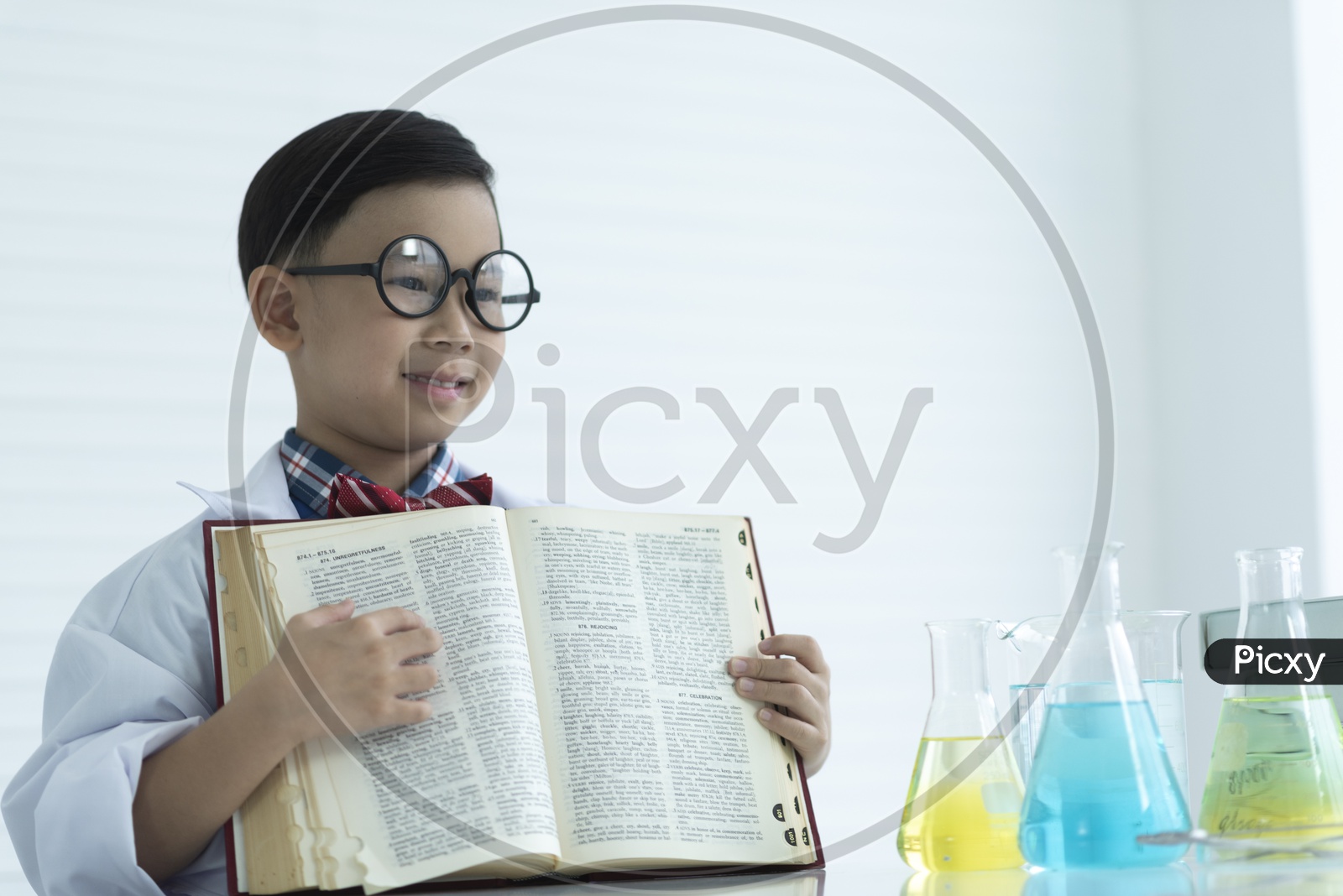 Asian nerdy boy holding a textbook in the classroom