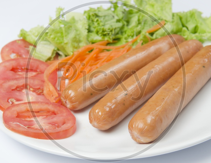 sausage and hot dogs garnished with vegetables isolated on white background