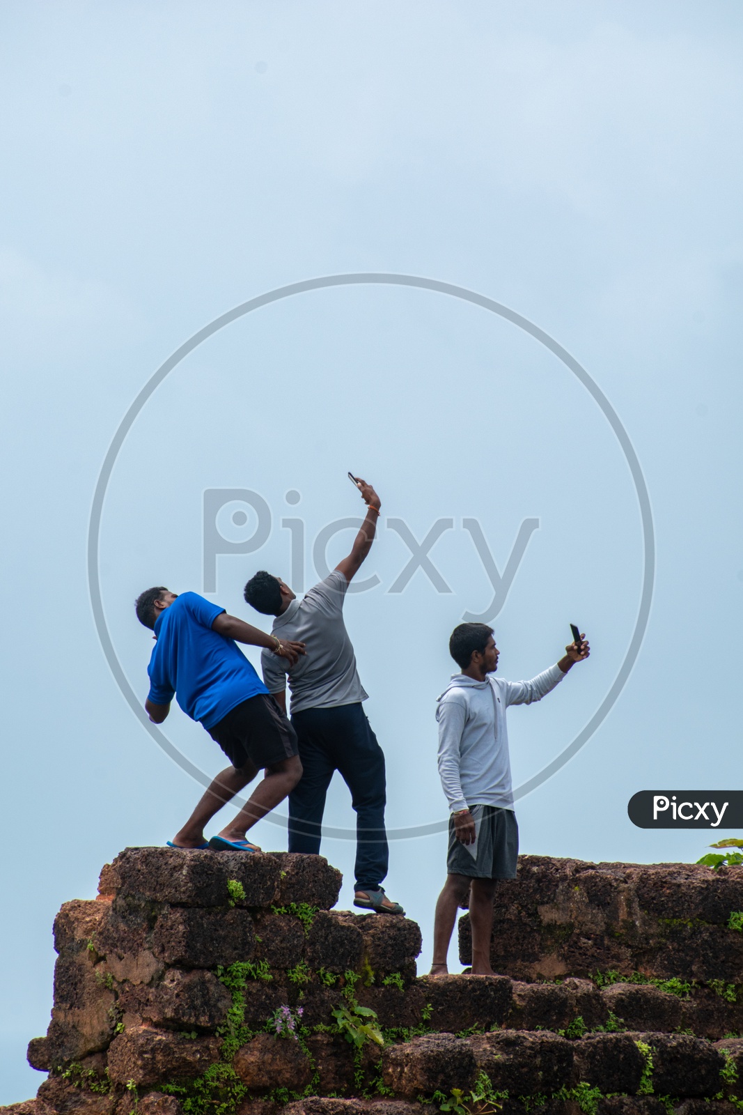 Young boys/men clicking selfies on the wall of Chapora Fort, Goa.