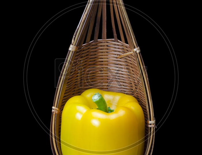 Capsicum in a wooden basket isolated on black background