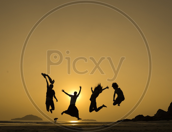 Silhouette of Group of young people jumping with joy at the beach during sunset in Thailand