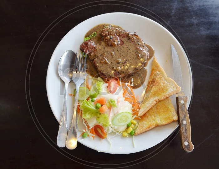Grilled Beaf Steak Served With Fresh Salad  And Toasted Bread Slices