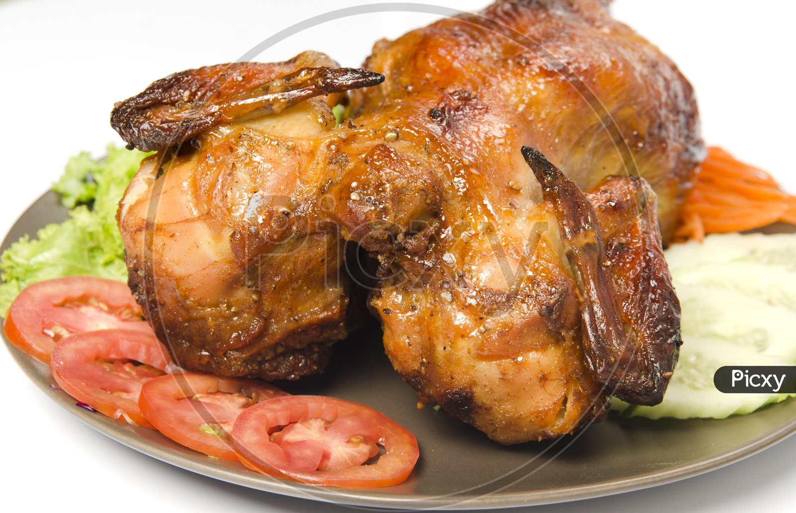 whole grilled chicken garnished with vegetables in plate