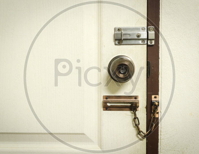 A Padlock on white door with chain