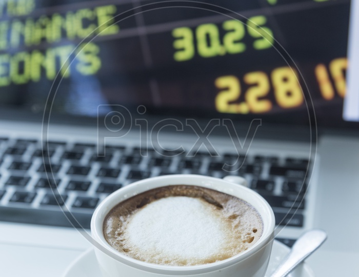 A Coffee Cup with Stock Markets Data on Laptop Screen