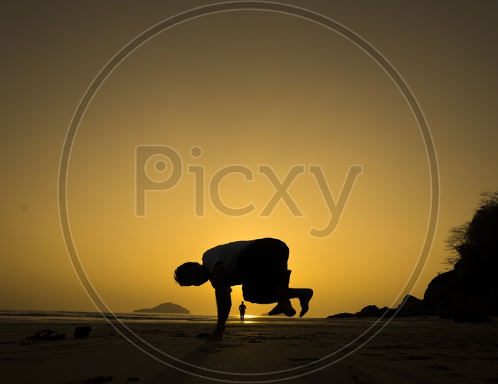Silhouette of a Young man doing YOGA during summer sunset