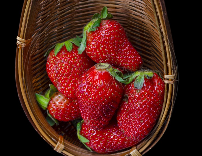 Fresh Strawberry in a wooden basket isolated on black background