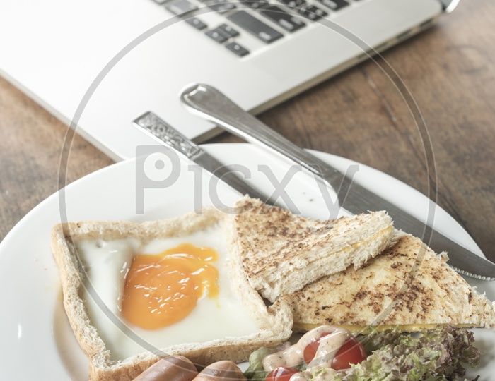 American Breakfast With Bread Omelet  And Fresh Veggies With a Laptop On Table