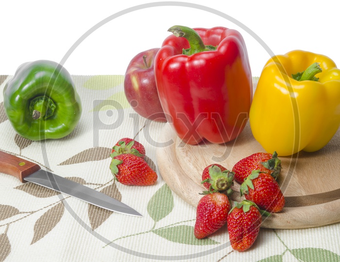 Capsicums, Apple and Strawberry on chopping block in the kitchen, Knife