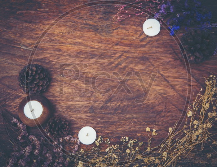 Dry flowers and candles frame on wood background with vintage filter effect