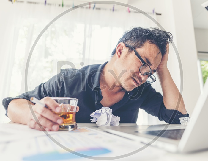 A disappointed Businessman holding a glass of whiskey