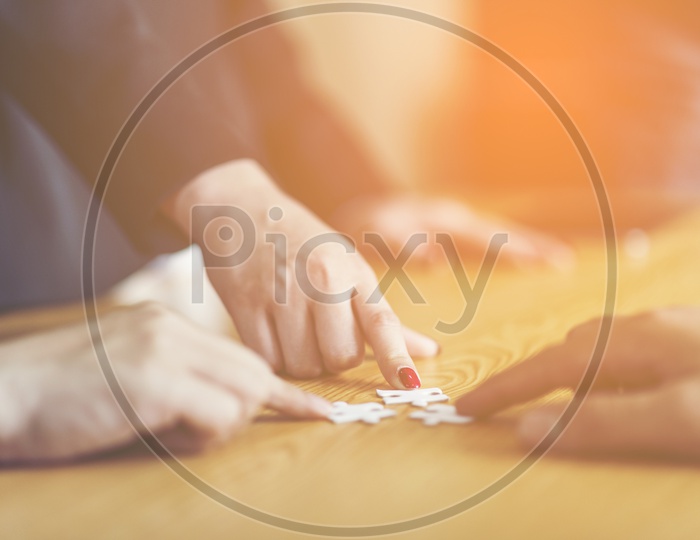 Businesspeople Hand Solving Jigsaw Puzzle On Wooden Desk, business concept