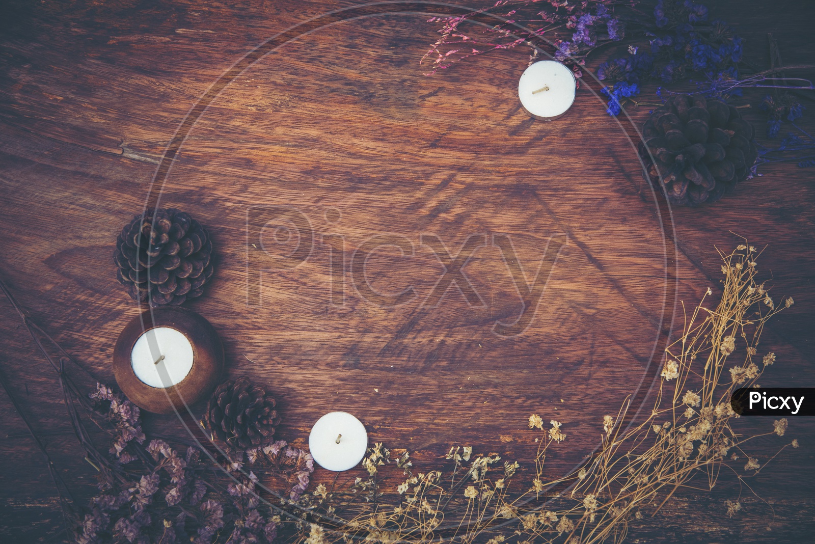 Dry flowers and candles frame on wood background with vintage filter effect