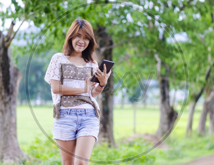 Asian woman posing with her tablet in the garen