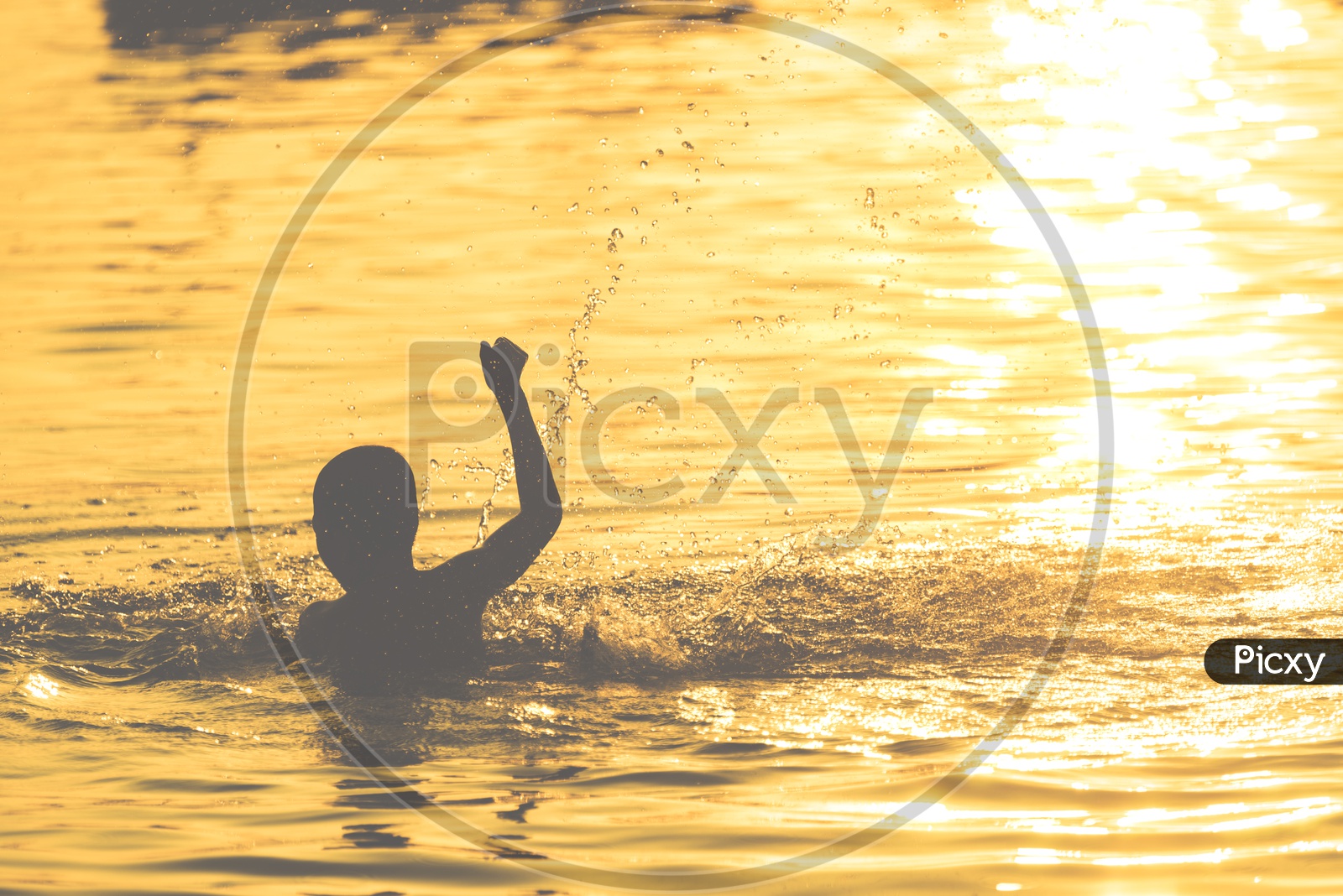 Silhouette Of a Boy Child Swimming In a Lake Over Bright Sunset Light