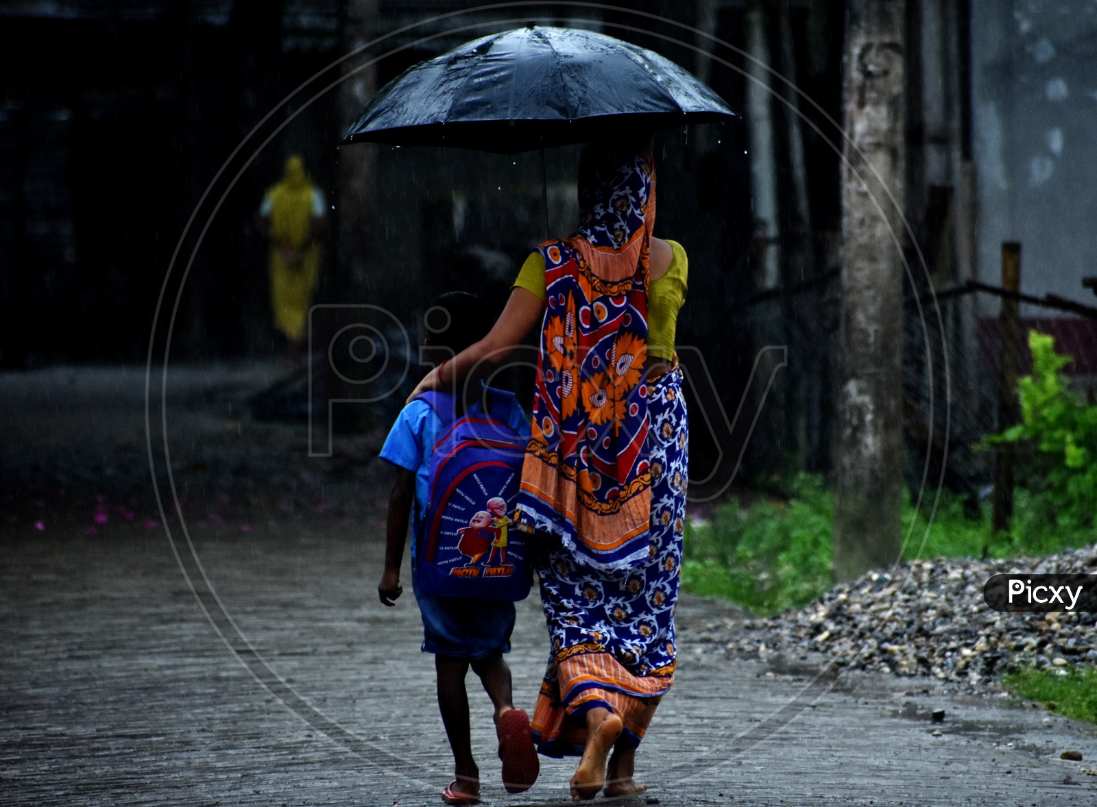 In a wet/ rainy morning a mother took her son to the school holding the umbrella over their heads .
