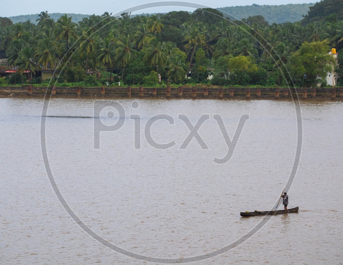 Fisherman fishing on the banks of Chapora river under Siolim bridge, Chopdem, Goa