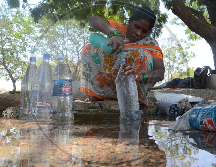 Woman Filling  Drinking Water to Bottles From a Overflowing Pipeline In Hyderabad City