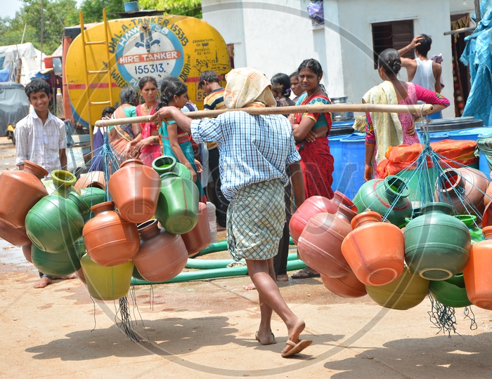A Vendor Carrying Plastic Water Storage  Vessels on His Shoulder At Water Crisis Areas Of  Hyderabad City