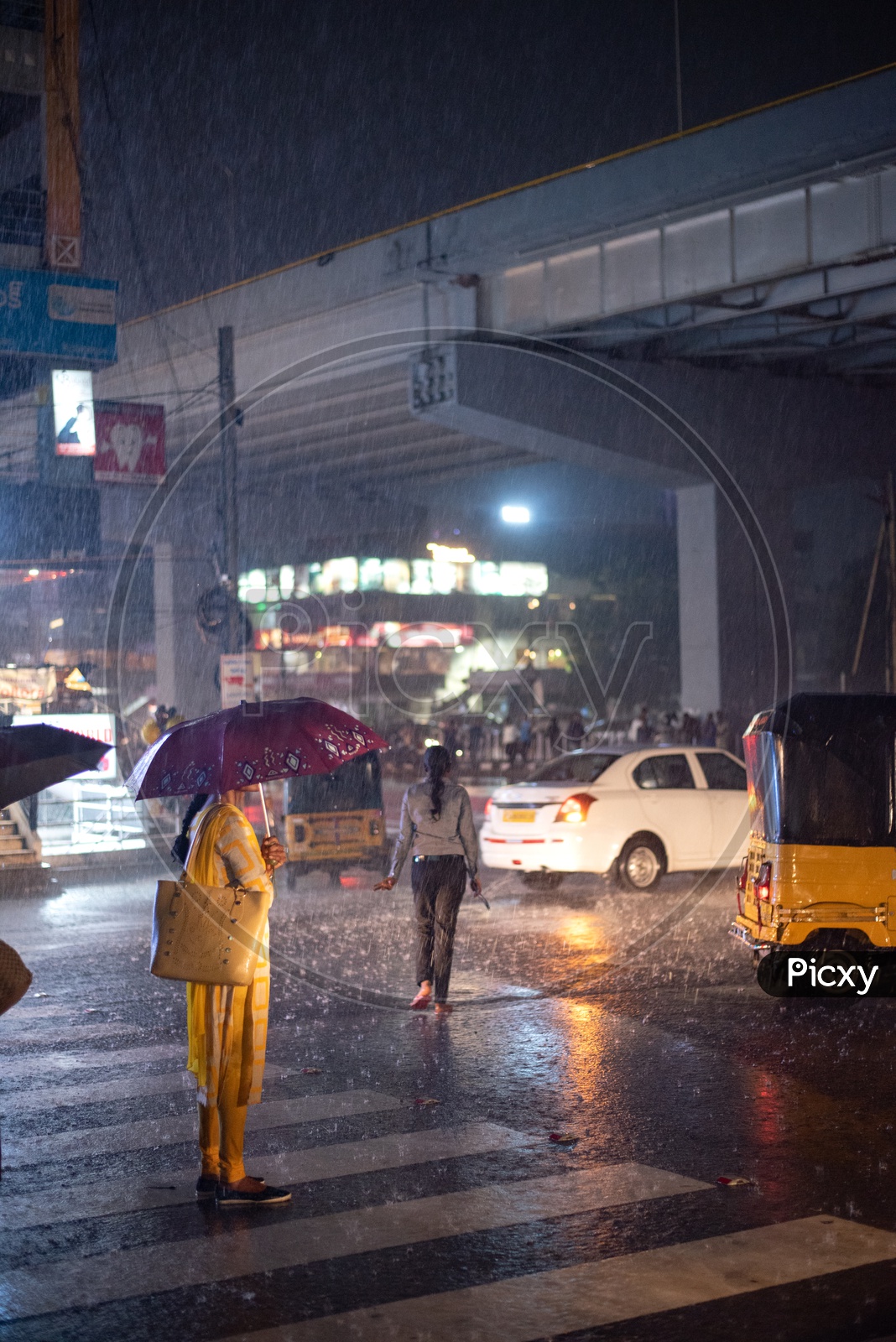 Woman Waiting For Public Commute Vehicle on road In Heavy Rain With an Umbrella