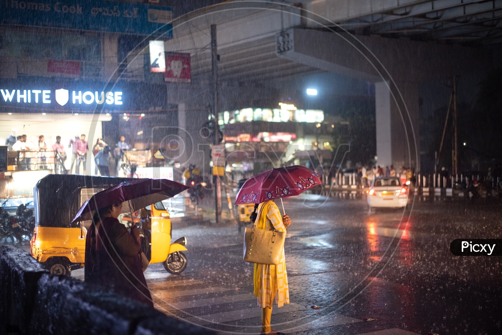 Woman Waiting For Public Commute Vehicle on road In Heavy Rain With an Umbrella