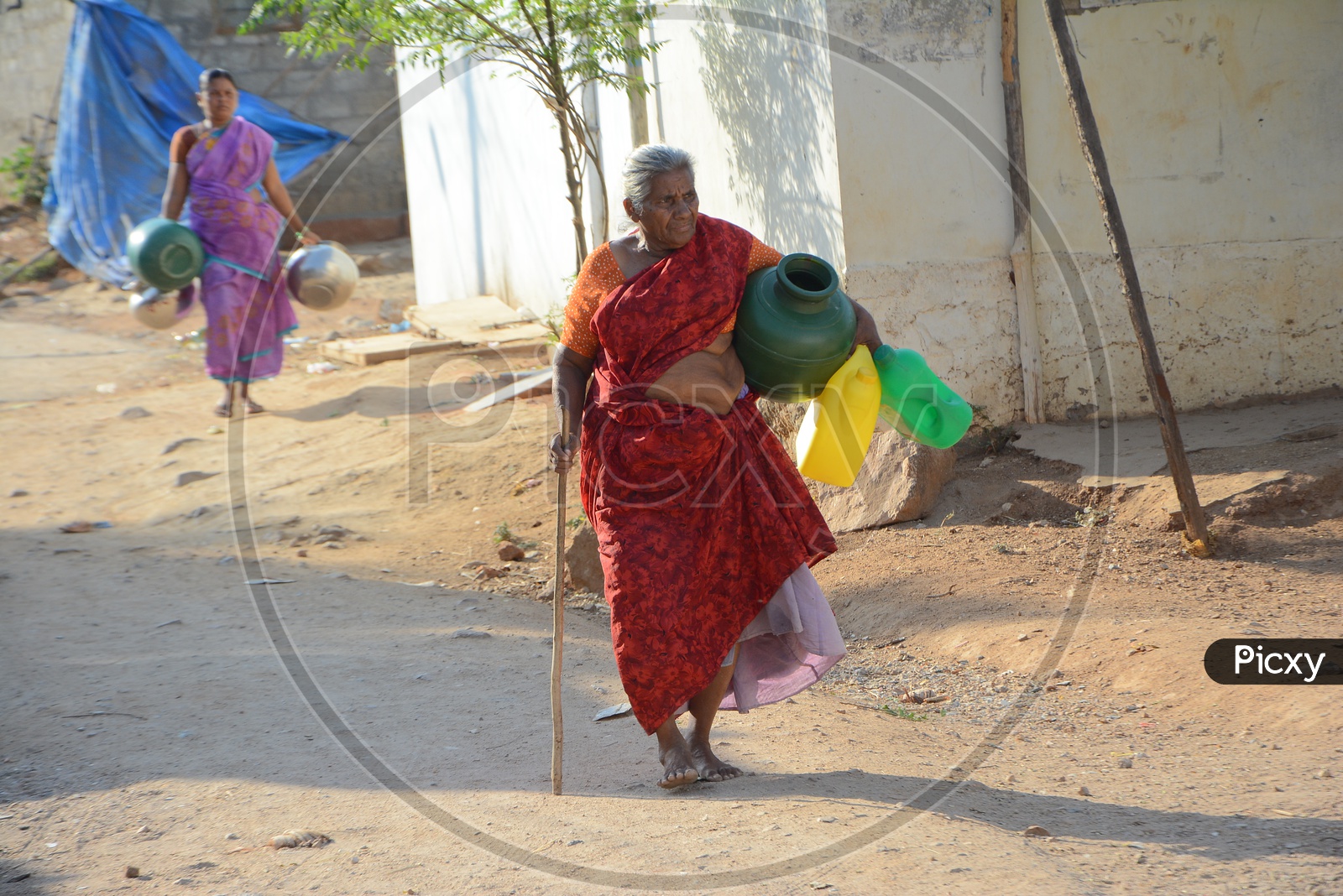 An Old Woman Carrying drinking water in Plastic Vessels At Water Crisis Areas Of Hyderabad
