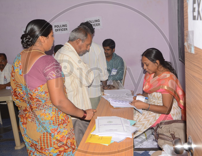 Voters Voting In a Polling Booth With Election Officers Checking Credentials