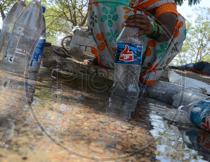 Woman Filling  Drinking Water to Bottles From a Overflowing Pipeline In Hyderabad City