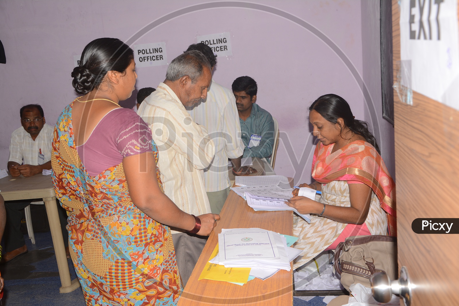 Voters Voting In a Polling Booth With Election Officers Checking Credentials