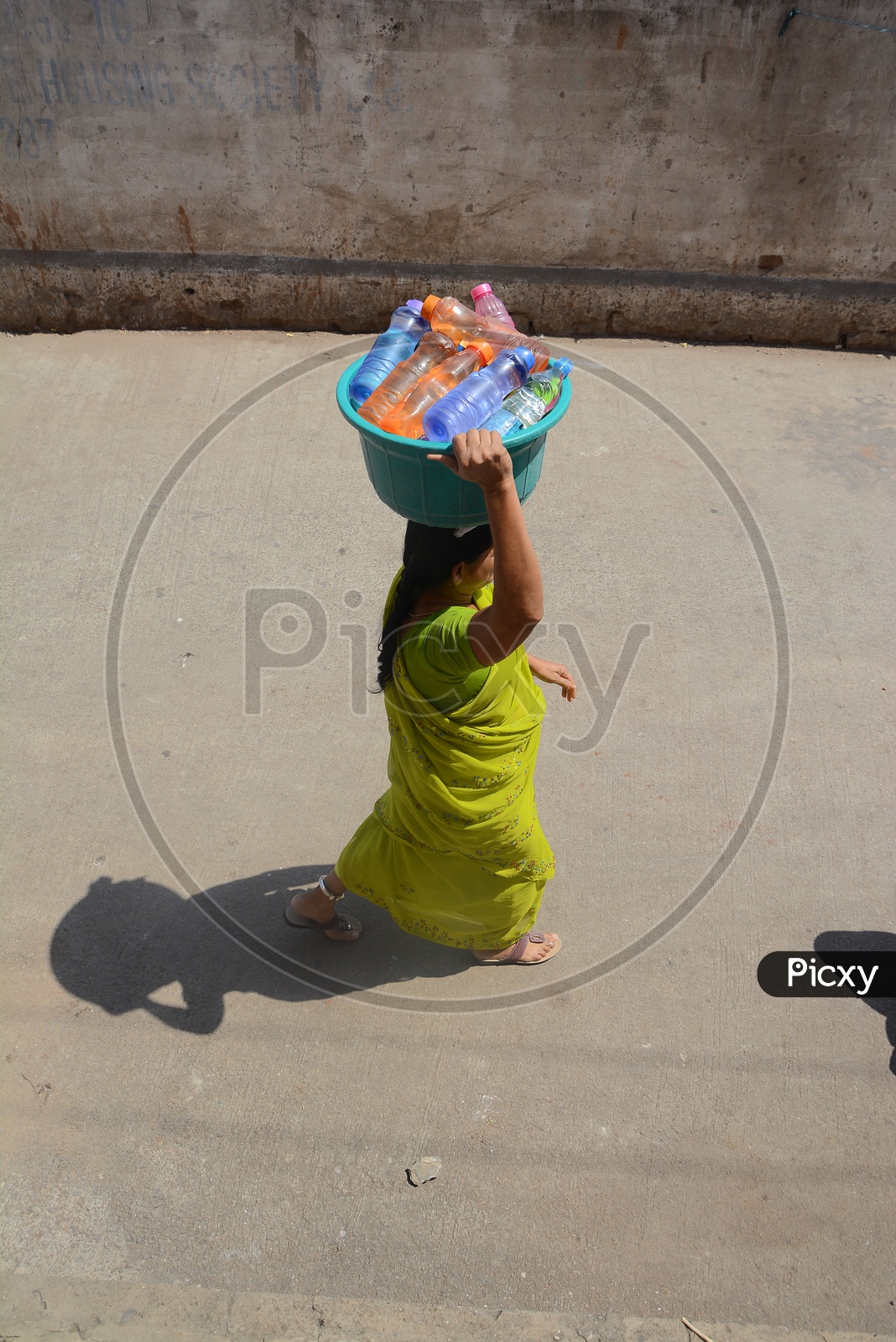Woman Carrying Water filled Pet Bottles For Drinking Purpose In Hyderabad
