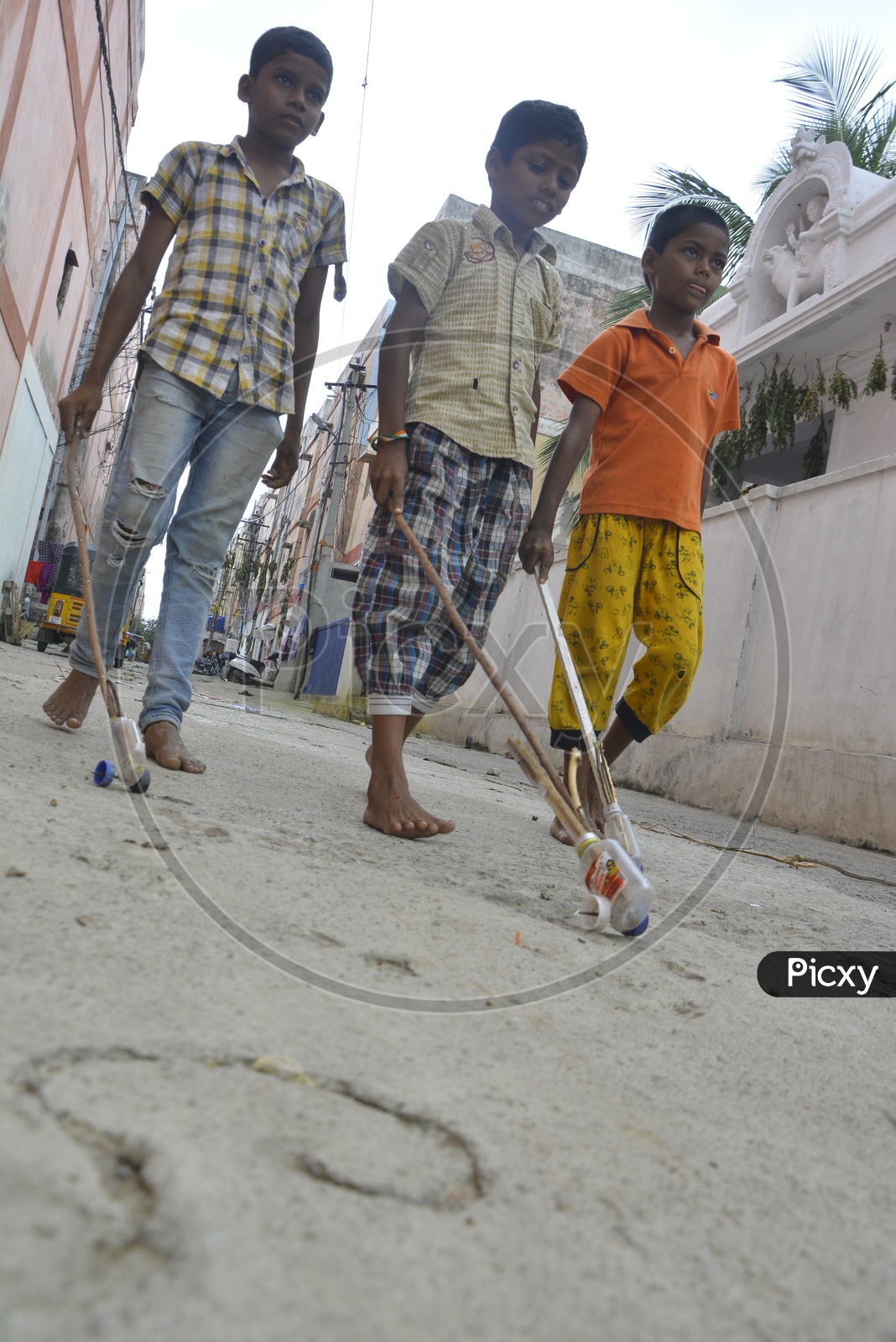 Indian Children Playing With Rolling Wheels Made Of Bottle Cap and Wooden Sticks on Streets