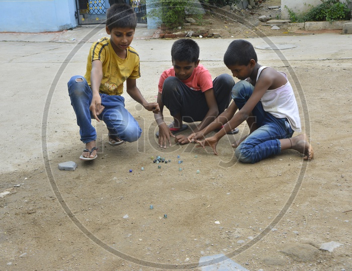 Indian Children Playing Marble Striking Game On Streets
