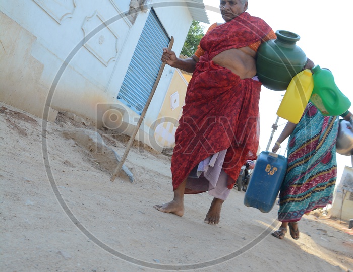 An Old Woman Carrying drinking water in Plastic Vessels At Water Crisis Areas Of Hyderabad
