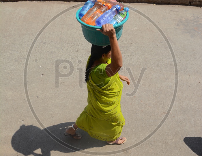 Woman Carrying Water filled Pet Bottles For Drinking Purpose In Hyderabad